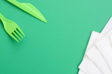 Tek kullanımlık plastik çatal bıçak takımı yeşil. Peçete yanındaki yeşil renkli yüzeyinde plastik çatal ve bıçak yalan