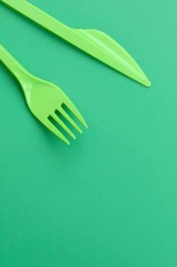 Tek kullanımlık plastik çatal bıçak takımı yeşil. Plastik çatal ve bıçak bir yeşil arka yüzeyinde yalan