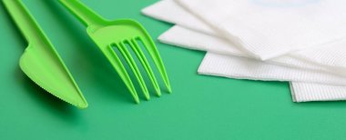 Tek kullanımlık plastik çatal bıçak takımı yeşil. Peçete yanındaki yeşil renkli yüzeyinde plastik çatal ve bıçak yalan