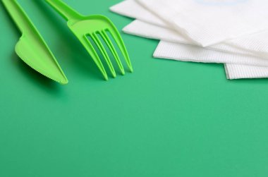 Tek kullanımlık plastik çatal bıçak takımı yeşil. Peçete yanındaki yeşil renkli yüzeyinde plastik çatal ve bıçak yalan
