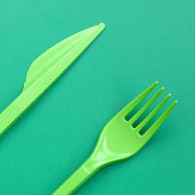 Tek kullanımlık plastik çatal bıçak takımı yeşil. Plastik çatal ve bıçak bir yeşil arka yüzeyinde yalan
