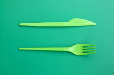 Tek kullanımlık plastik çatal bıçak takımı yeşil. Plastik çatal ve bıçak bir yeşil arka yüzeyinde yalan