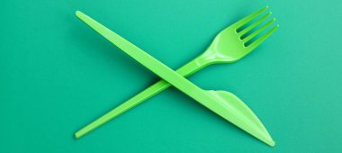 Tek kullanımlık plastik çatal bıçak takımı yeşil. Plastik çatal ve bıçak bir yeşil arka yüzeyinde yalan