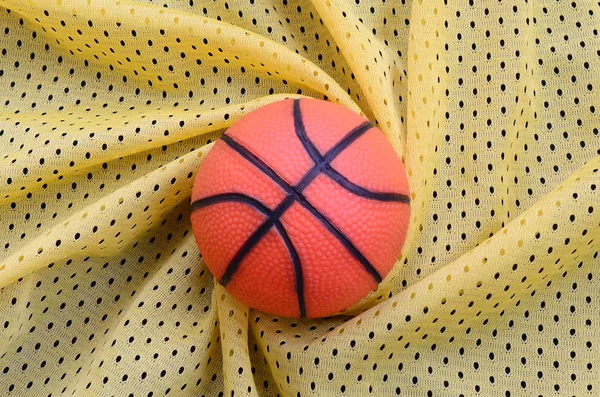 Маленький Оранжевый Резиновый Баскетбол Лежит Желтой Спортивной Трикотажной Ткани Одежды — стоковое фото