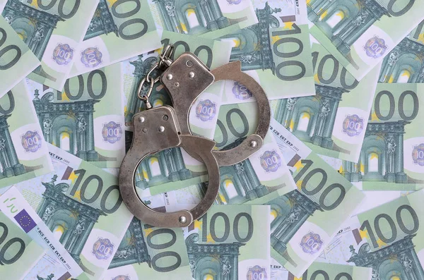 Die Handschellen der Polizei klickten auf einem grünen Geldschein im Wert von 100 Euro. Viel Geld bildet einen unendlichen Haufen — Stockbild Die Handschellen Der Polizei Klickten Auf Einem Grünen Geldschein Wert — Stockfoto