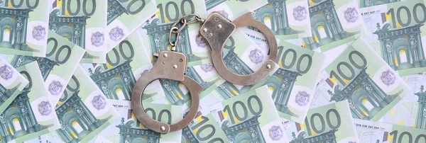 Полицейские наручники лежат на наборе зеленых денежных деноминаций — стоковое фото