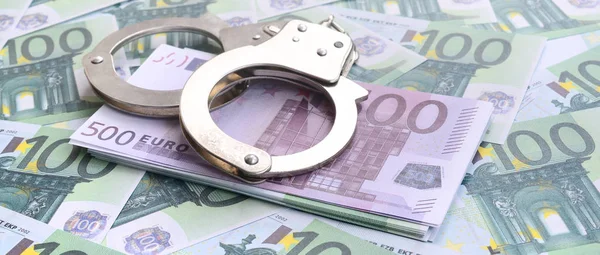 Полицейские наручники лежат на наборе зеленых денежных деноминаций — стоковое фото