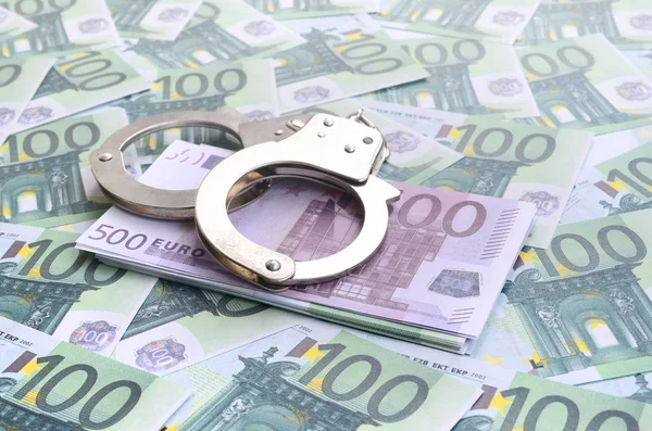 Die Handschellen der Polizei klickten auf einem grünen Geldschein im Wert von 100 Euro. Viel Geld bildet einen unendlichen Haufen — Stockbild Die Handschellen Der Polizei Klickten Auf Einem Grünen Geldschein Wert — Stockfoto