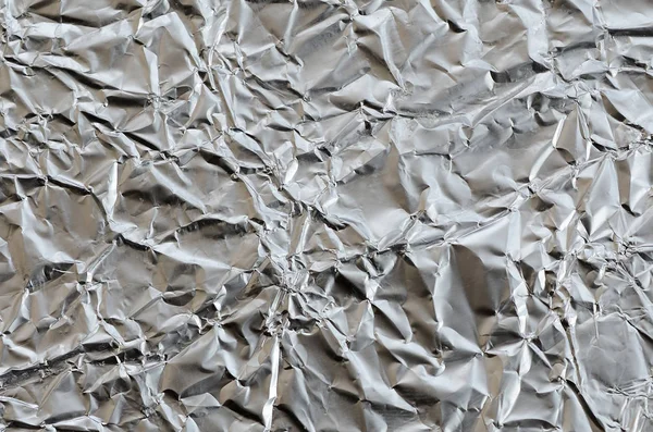 Thin wrinkled sheet of crushed tin aluminum silver foil backgrou — Stock Photo, Image