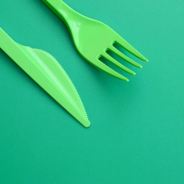 使い捨てのプラスチック製食器グリーン。プラスチックのフォークとナイフに寝そべって — ストック写真