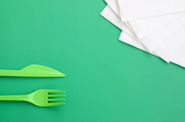 Cubertería de plástico desechable verde. Tenedor de plástico y cuchillo se encuentran en — Foto de Stock