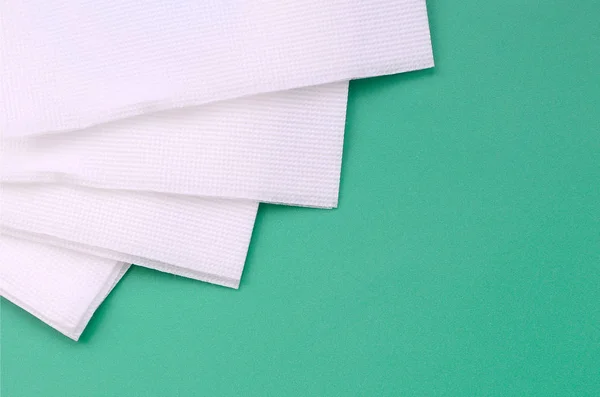 Several white paper napkins lie on a plastic green background — Stock Photo, Image