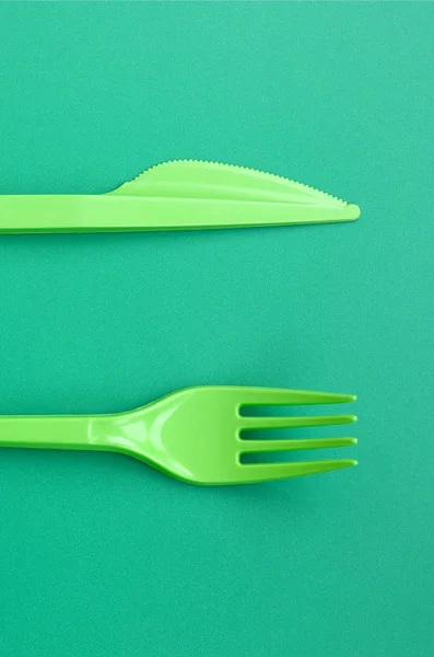 Einweg-Besteck aus Kunststoff grün. Plastikgabel und Messer liegen auf — Stockfoto