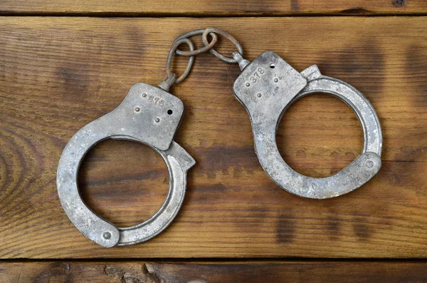 Old Rusty Police Handcuffs Lie Scratched Wooden Surface Concept Old — Stock Photo, Image