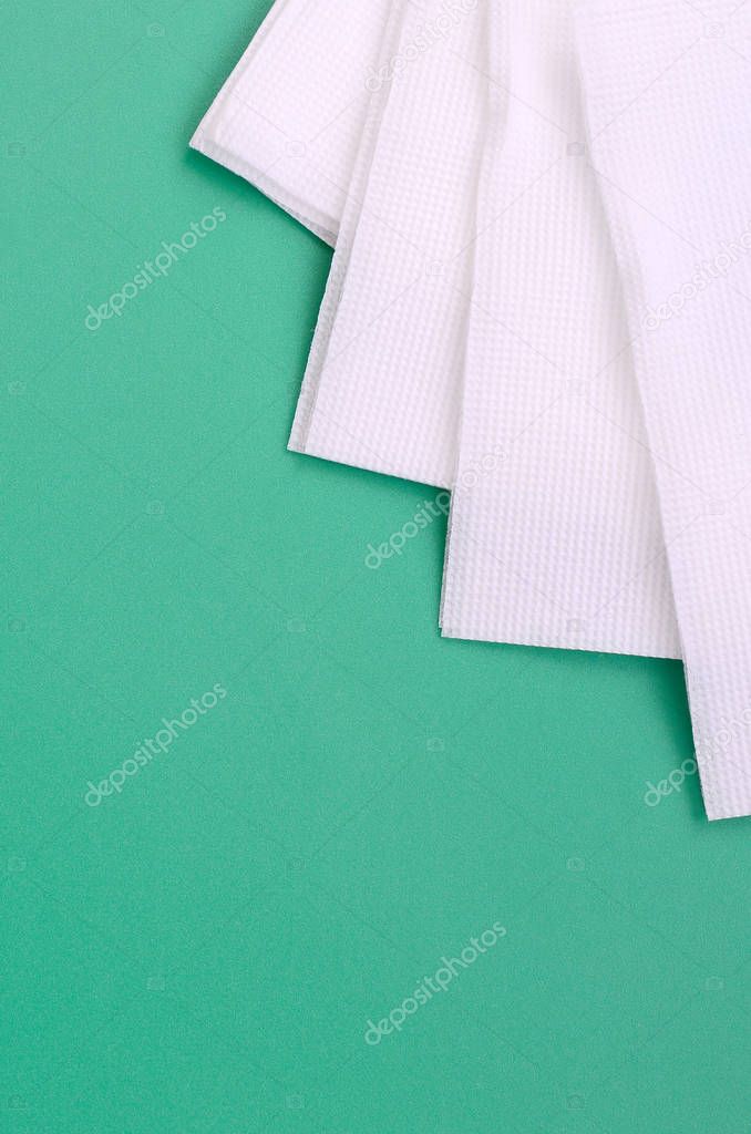 Several white paper napkins lie on a plastic green background