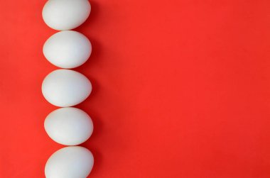 Parlak kırmızı bir arka plan üzerinde bir çok beyaz yumurta