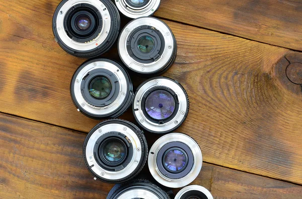 Varias lentes fotográficas se encuentran sobre un fondo de madera marrón. Sp —  Fotos de Stock