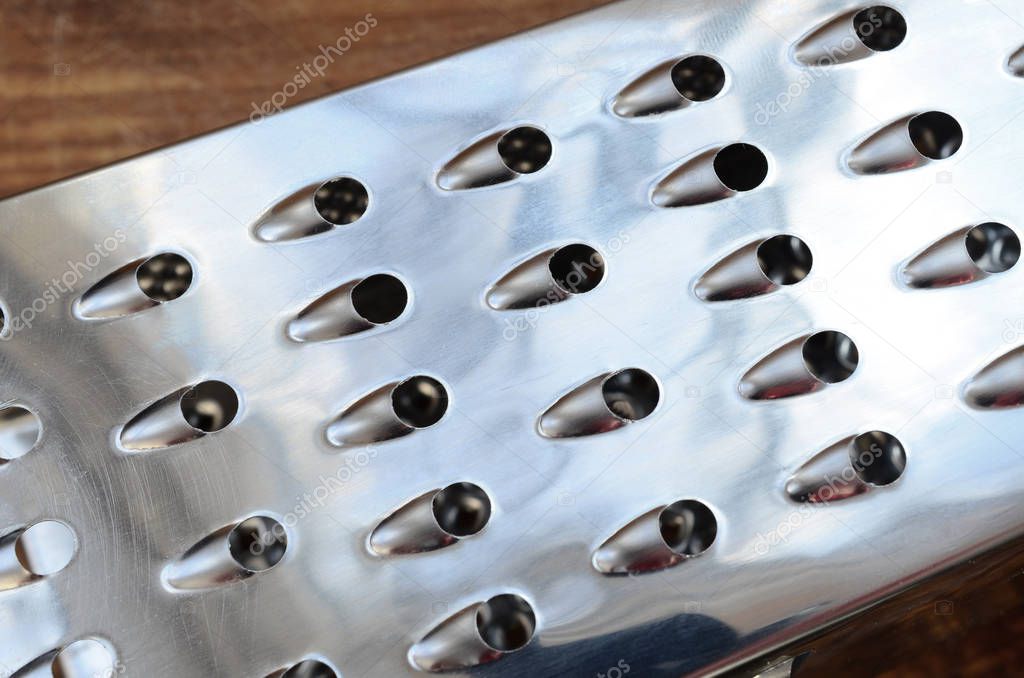 A fragment of a metal chrome grater close-up. Texture of blades for grinding food