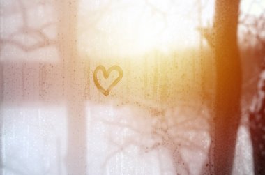 Heart is painted on the misted glass in the winter clipart