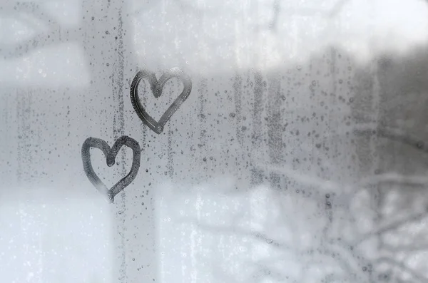 两颗心在冬天的迷离玻璃上作画 — 图库照片