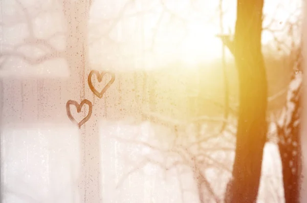 Deux cœurs peints sur un verre brumeux en hiver — Photo