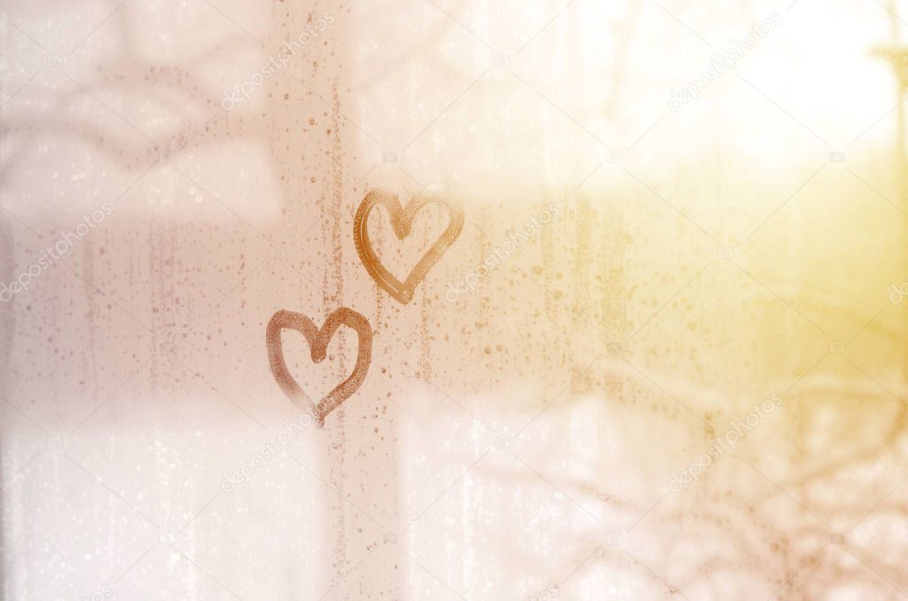 Two hearts painted on a misted glass in winter