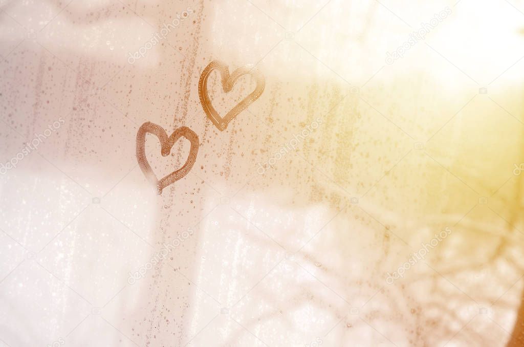 Two hearts painted on a misted glass in winter