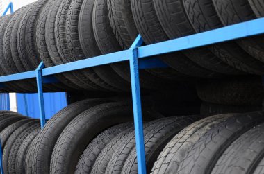 Otomobil mağazasında çeşitli araba lastikleriyle dolu raflar. Bir sürü siyah lastik. Lastik yığını arka planı. Seçici odak