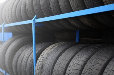 Otomobil mağazasında çeşitli araba lastikleriyle dolu raflar. Bir sürü siyah lastik. Lastik yığını arka planı. Seçici odak