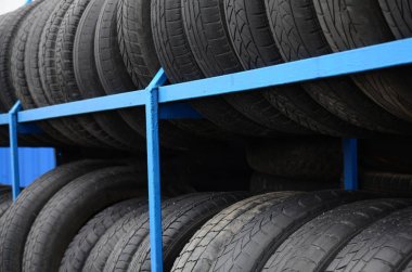 Otomobil mağazasında çeşitli araba lastikleriyle dolu raflar. Bir sürü siyah lastik. Lastik yığını arka planı. Seçici odak