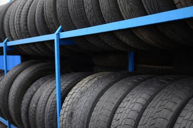 Otomobil mağazasında çeşitli araba lastikleriyle dolu raflar. Bir sürü siyah lastik. Lastik yığını arka planı. Seçici odak