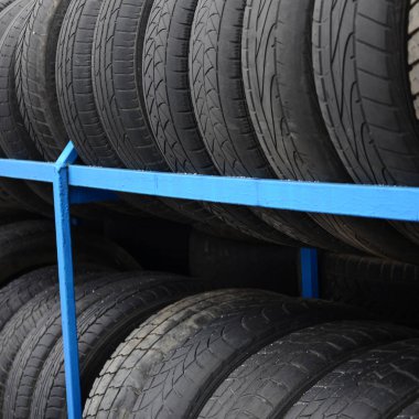 Otomobil mağazasında çeşitli araba lastikleriyle dolu raflar. Bir sürü siyah lastik. Lastik yığını arka planı. Seçici odak
