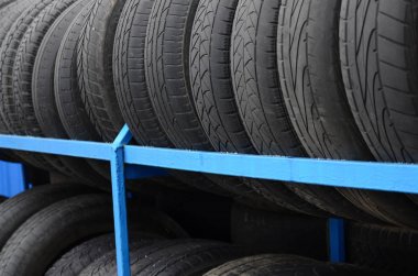 Otomobil mağazasında çeşitli araba lastikleriyle dolu raflar. Bir sürü siyah lastik. Lastik yığını arka planı. Seçici odak