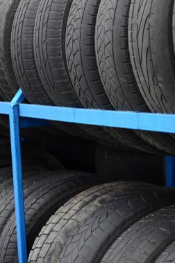 Otomobil mağazasında çeşitli araba lastikleriyle dolu raflar. Bir sürü siyah lastik. Lastik yığını arka planı. Seçici odak