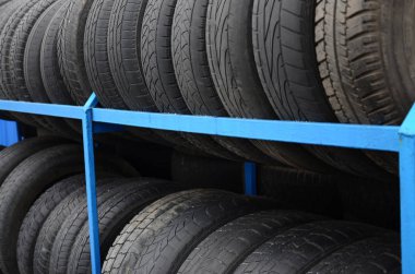 Otomobil mağazasında çeşitli araba lastikleriyle dolu raflar. Bir sürü siyah lastik. Lastik yığını arka planı. Seçici odak