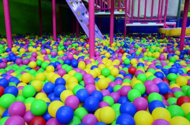 Çocuk parkındaki top havuzunda bir sürü renkli plastik top var.