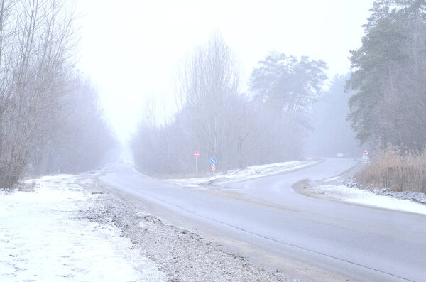 Перекресток на пригородной асфальтовой дороге зимой во время метели
