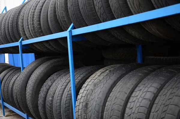 Rack with variety of car tires in automobile store. Many black tires. Tire stack background. Selective focus