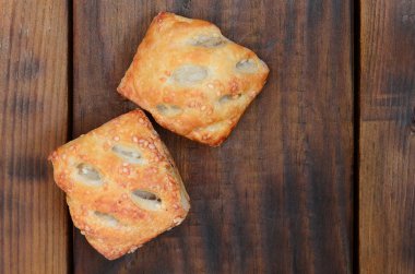 Tatmin edici bir etli börek, havadar poğaça ve leziz bir domuz eti ile soğanı birleştirir. Ahşap bir arka planda pişirme