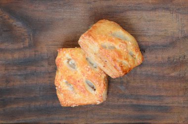 Tatmin edici bir etli börek, havadar poğaça ve leziz bir domuz eti ile soğanı birleştirir. Ahşap bir arka planda pişirme