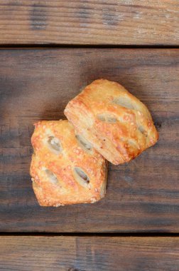 Tatmin edici bir etli börek, havadar poğaça ve leziz bir domuz eti ile soğanı birleştirir. Ahşap bir arka planda pişirme