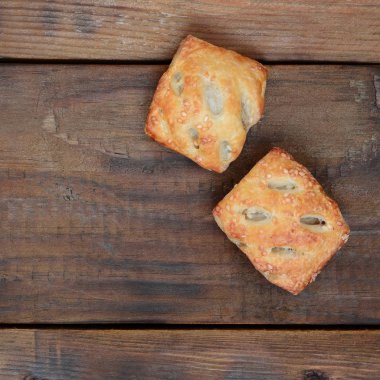 Tatmin edici bir etli börek, havadar poğaça ve leziz bir domuz eti ile soğanı birleştirir. Ahşap bir arka planda pişirme