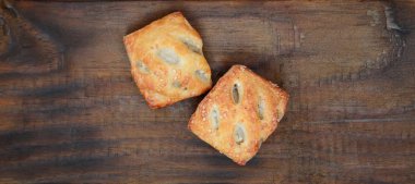 Tatmin edici bir etli börek, havadar poğaça ve leziz bir domuz eti ile soğanı birleştirir. Ahşap bir arka planda pişirme