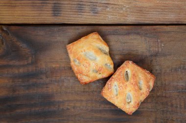 Tatmin edici bir etli börek, havadar poğaça ve leziz bir domuz eti ile soğanı birleştirir. Ahşap bir arka planda pişirme
