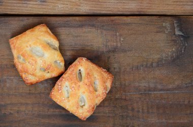Tatmin edici bir etli börek, havadar poğaça ve leziz bir domuz eti ile soğanı birleştirir. Ahşap bir arka planda pişirme
