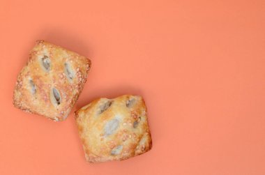 Havadar bir puf böreği ve hassas bir domuz doldurma soğan ile birleştiren bir tatmin et patty. Turuncu bir arka plan üzerinde pişirme