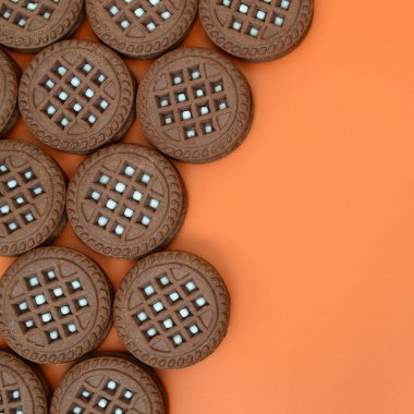 Ayrıntılı resmini koyu kahverengi ile turuncu bir yüzeye doldurma Hindistan cevizi sandviç kurabiye yuvarlak. Çay için birkaç muamele etmek bir close-up arka plan görüntüsü