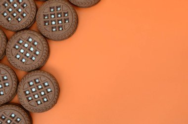 Ayrıntılı resmini koyu kahverengi ile turuncu bir yüzeye doldurma Hindistan cevizi sandviç kurabiye yuvarlak. Çay için birkaç muamele etmek bir close-up arka plan görüntüsü