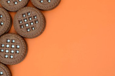 Ayrıntılı resmini koyu kahverengi ile turuncu bir yüzeye doldurma Hindistan cevizi sandviç kurabiye yuvarlak. Çay için birkaç muamele etmek bir close-up arka plan görüntüsü