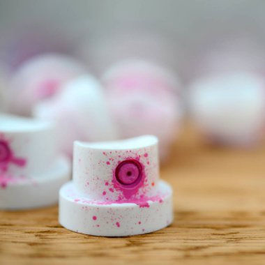 Kirli pembe boya püskürtme başlıklarından yatıyor birçok kirli sprey kutular bir arka plan üzerinde ahşap bir tahta üzerinde